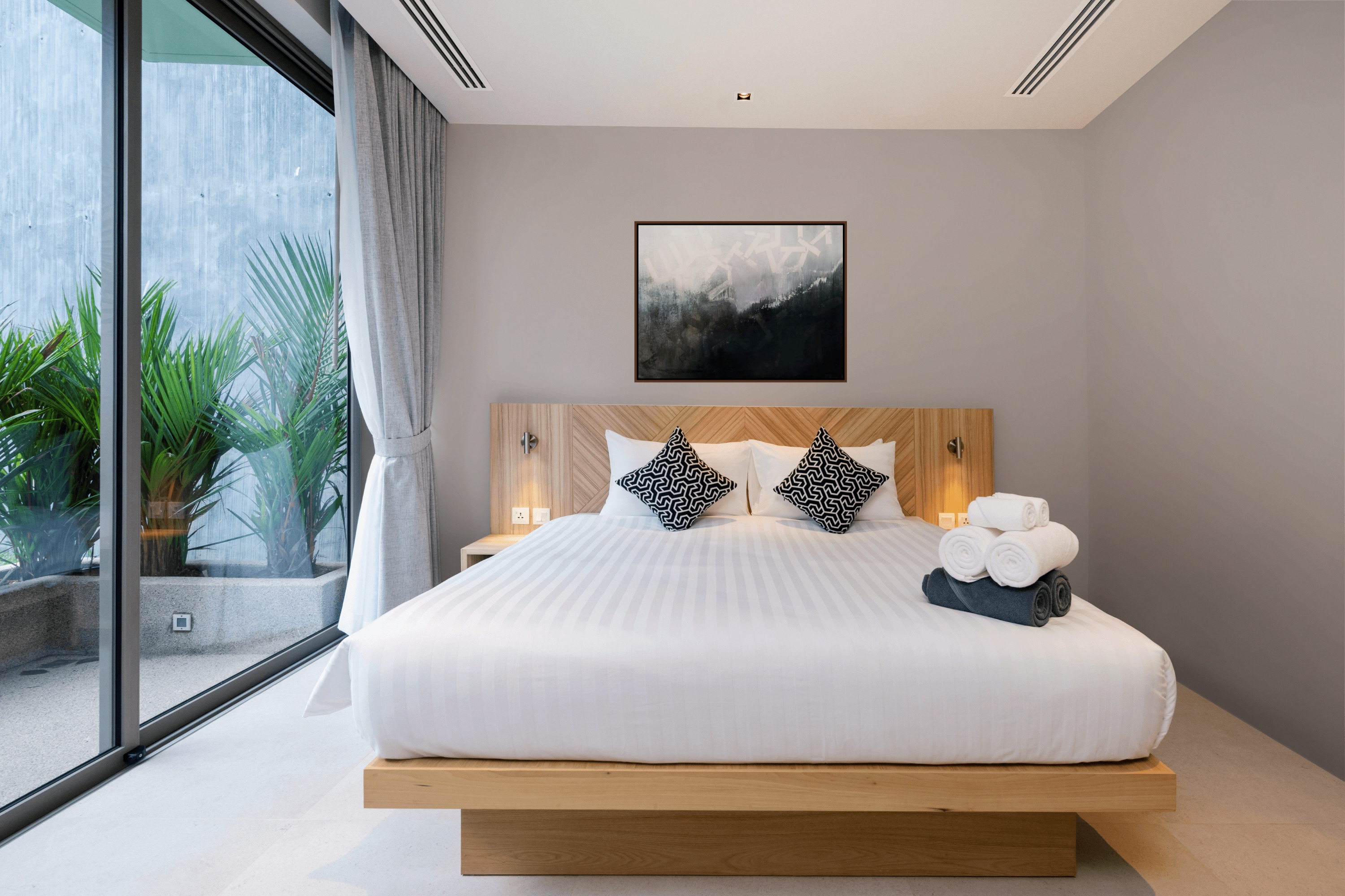 Captivity abstract artwork framed above minimal platform bed in a serene neutral bedroom retreat