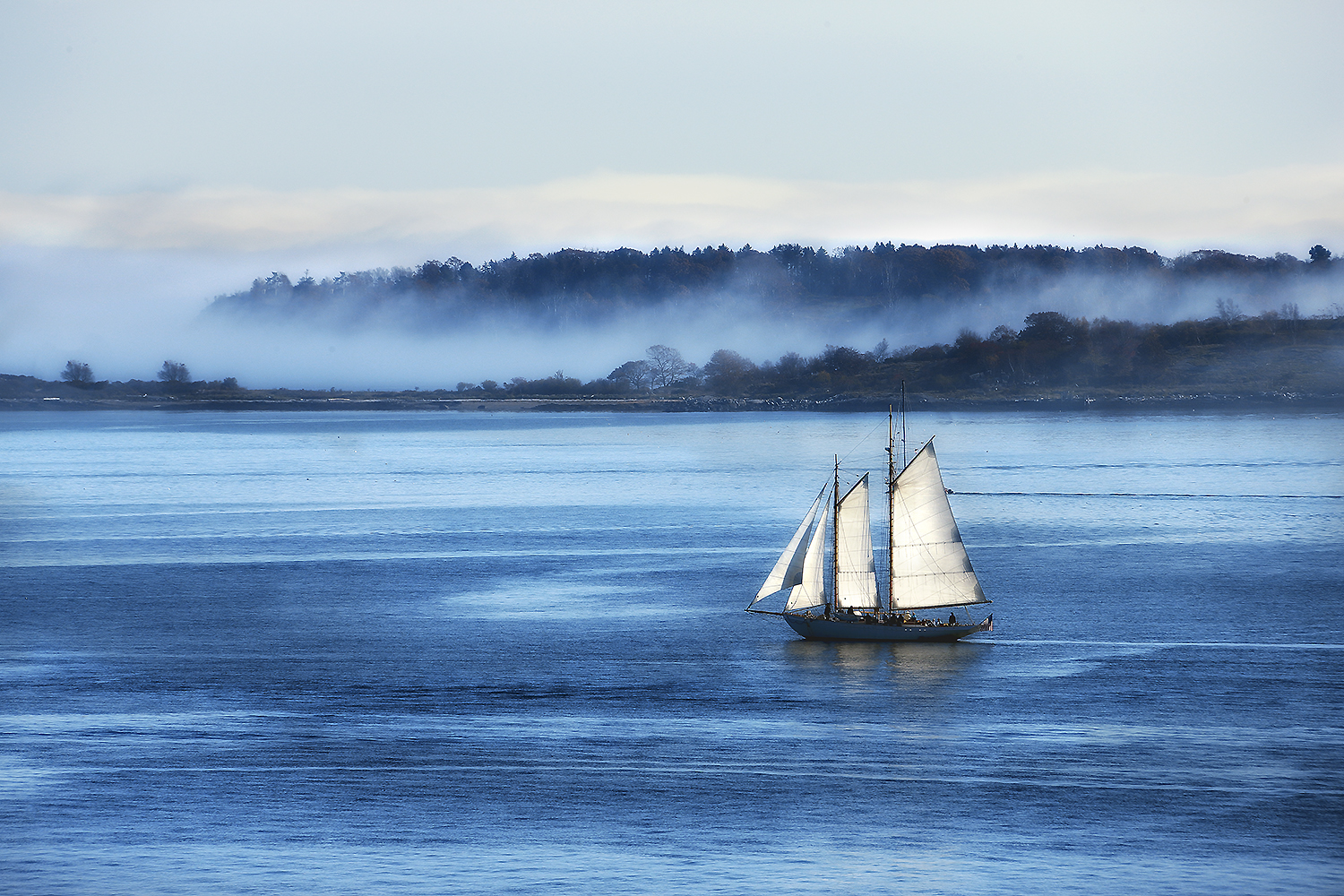 A sailing ship crossing calm blue water beneath a pale sky, evoking the quiet uncertainty of departure