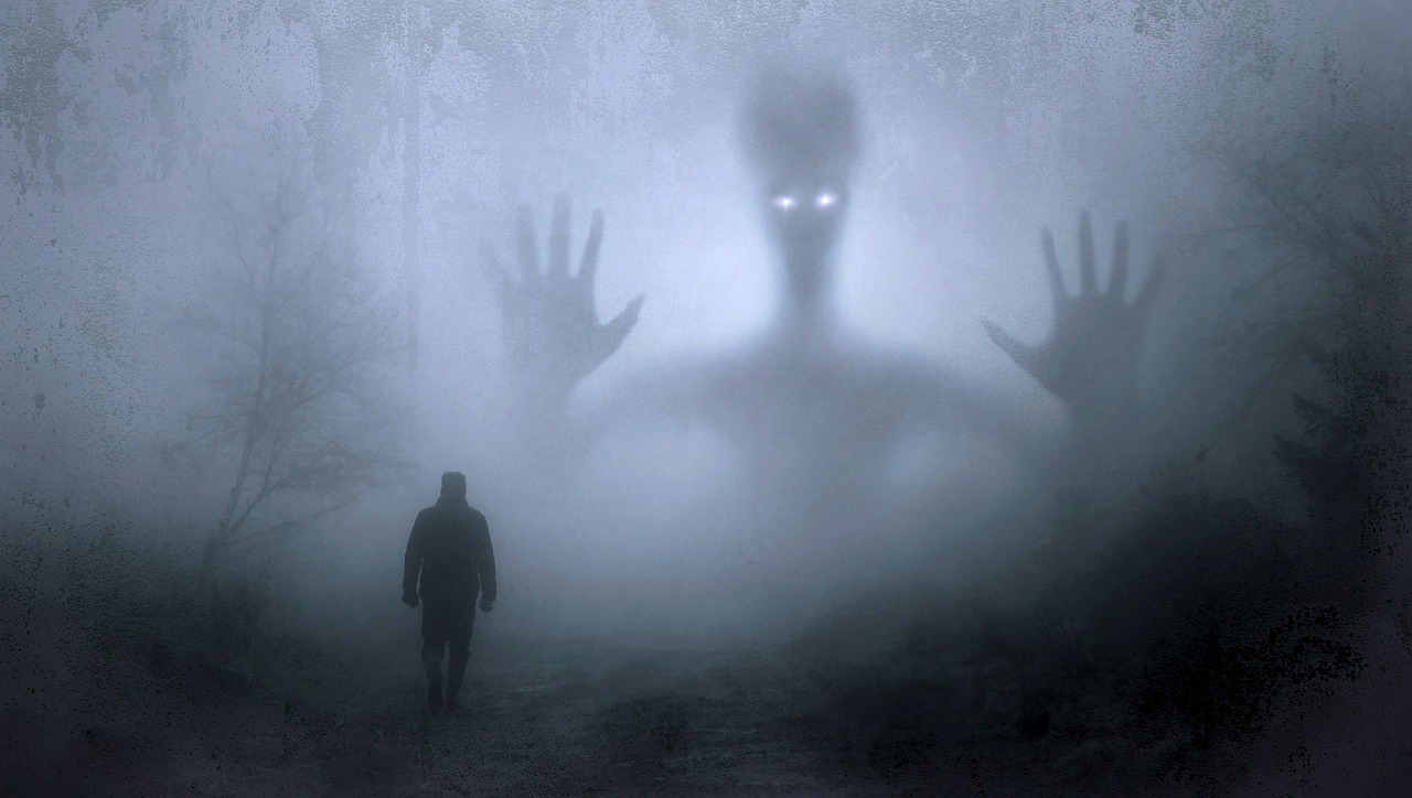 A misty scene where a figure walks in a wood. Behind a giant figure looms in.