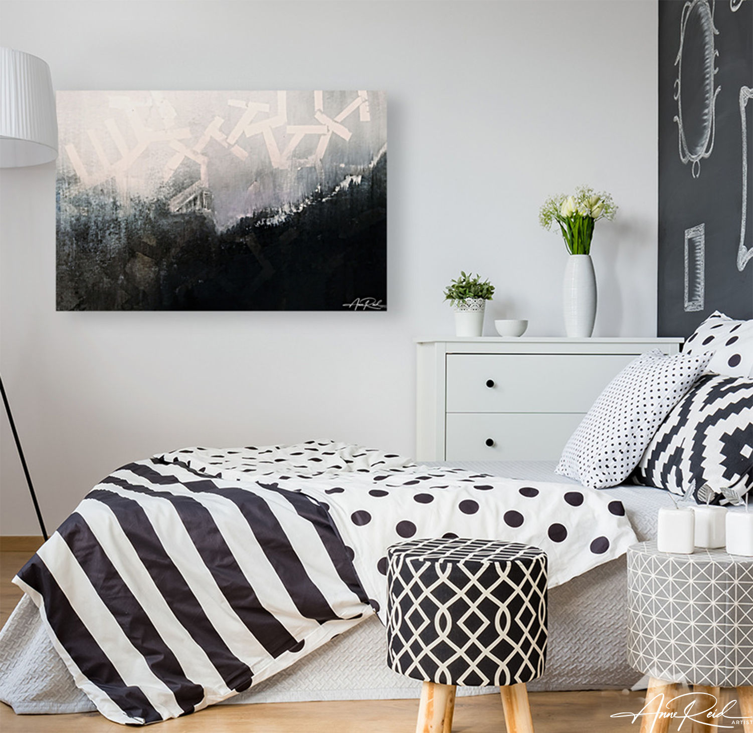 Black and white abstract painting above modern bed with monochrome geometric bedding