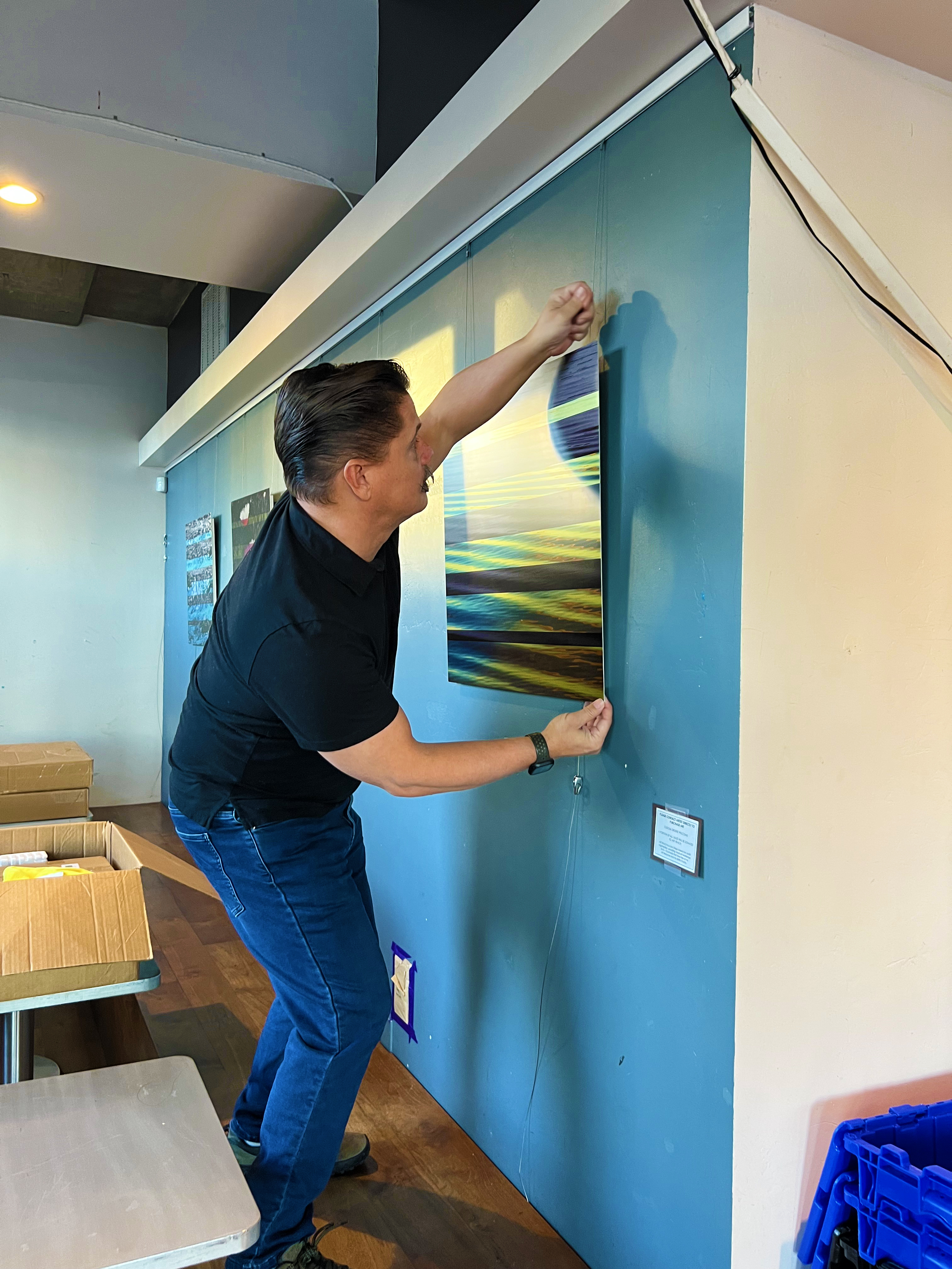 Artist Jon Savage installing 'Golden Reflections' original textured metal wall art at Bird Rock Coffee in Little Italy, San Diego.