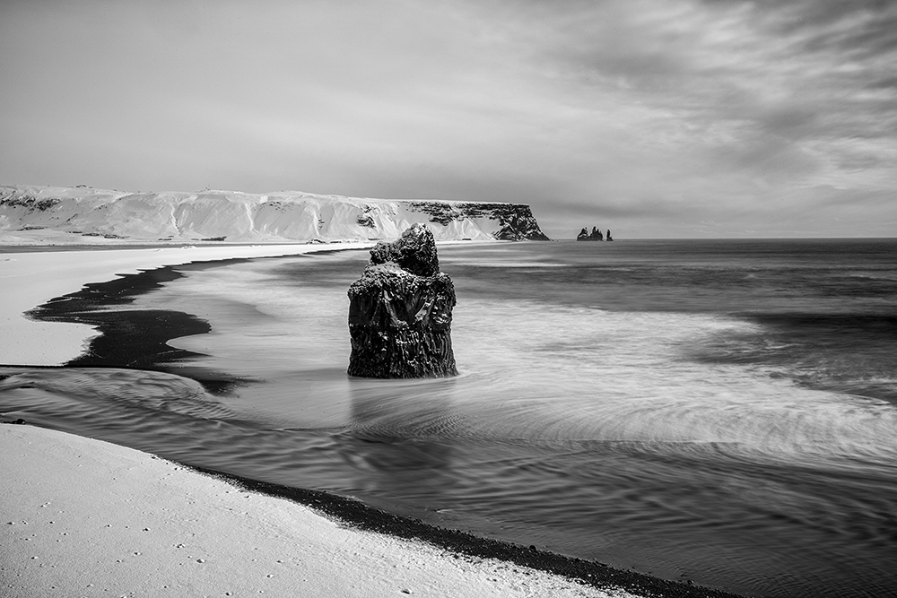 Wave spiraling over black beach in Iceland — nature’s imprint of Pi as motion and return