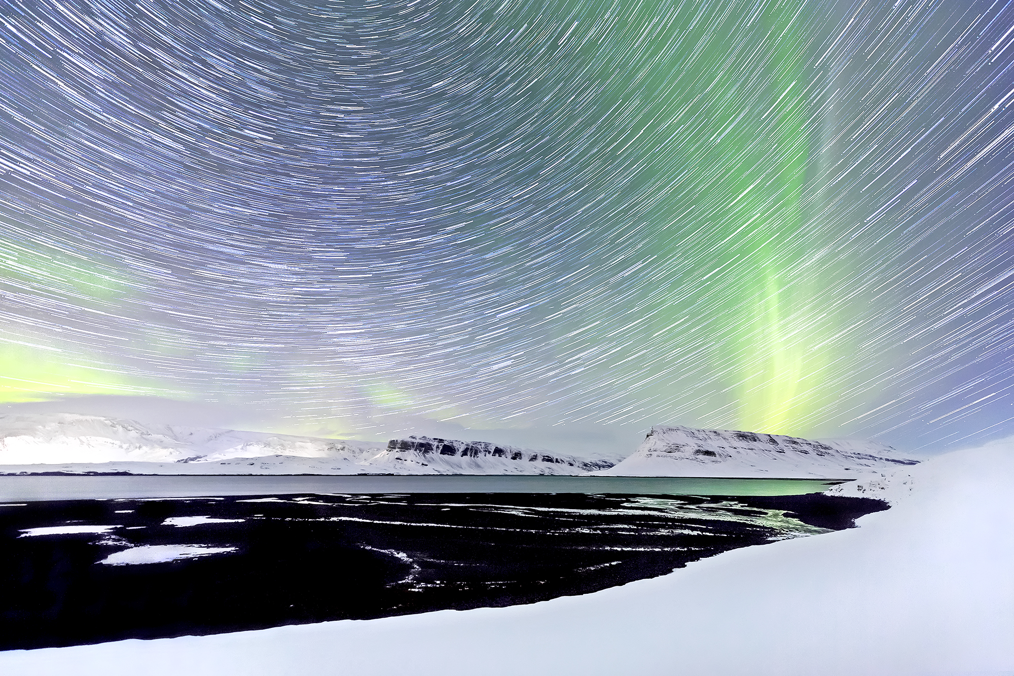 Star trails and aurora over snow-covered land—symbolizing planetary resonance and sacred geometry memory | Robbie George Photography