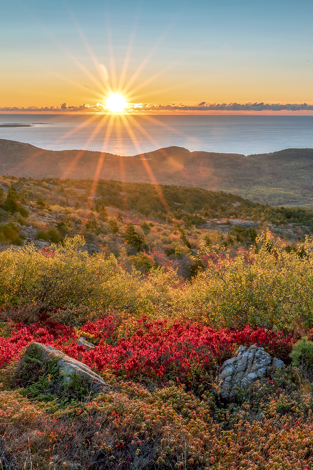 Sunrise light over Cadillac Mountain revealing granite ridges and Atlantic coastline in Acadia National Park