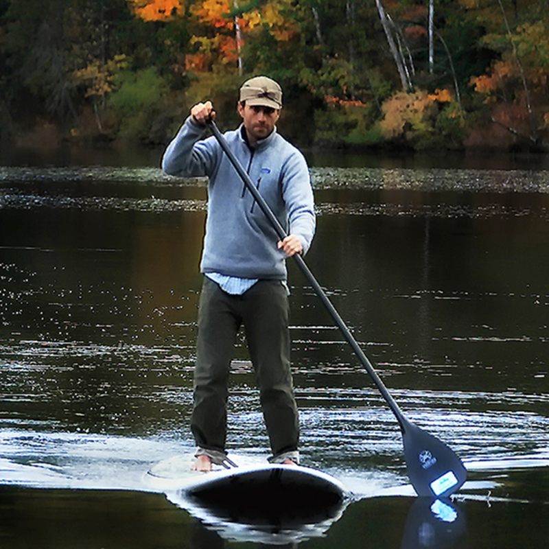 Robbie George paddle boarding on a quiet Maine lake—practicing Slow Knowledge