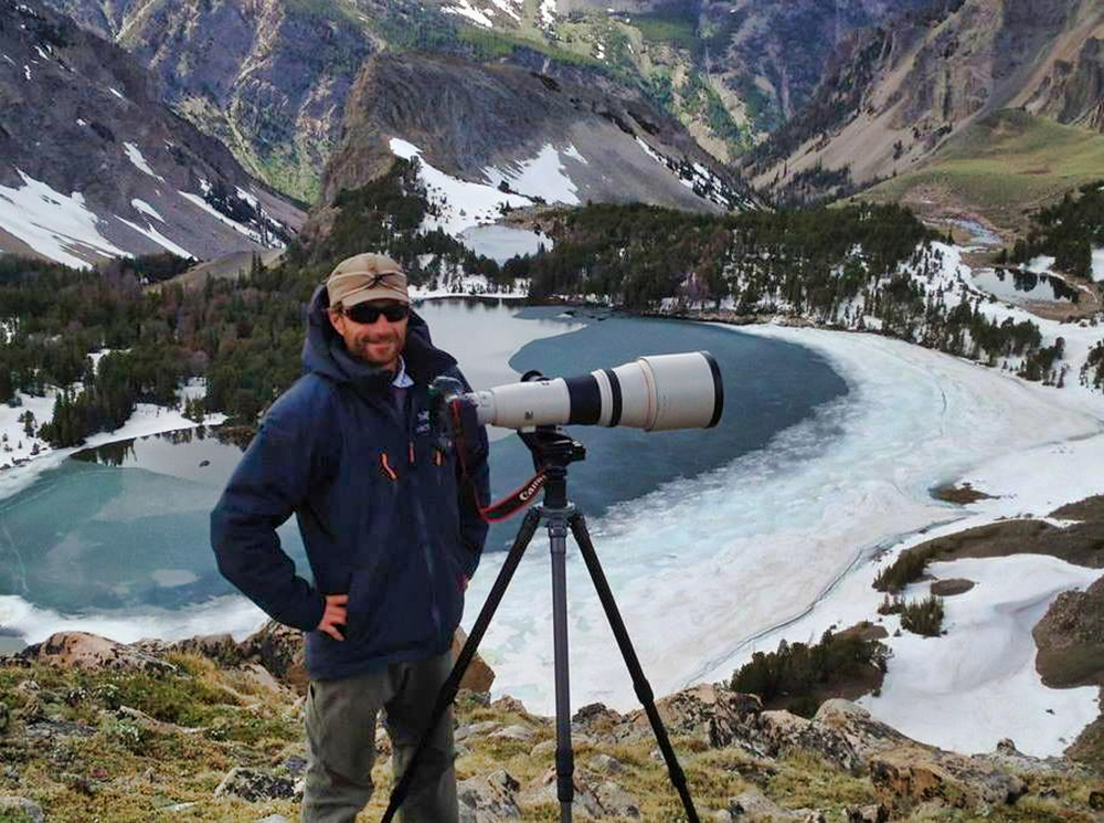 Camera tripod standing in snow during early morning field conditions, representing seasonal observation, patience, and photographic planning in winter