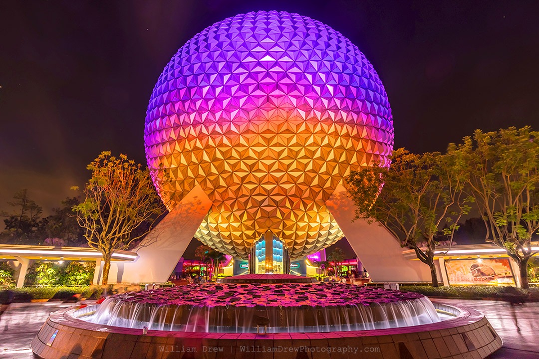 Disney wall art of Spaceship Earth glowing purple and gold at night in EPCOT