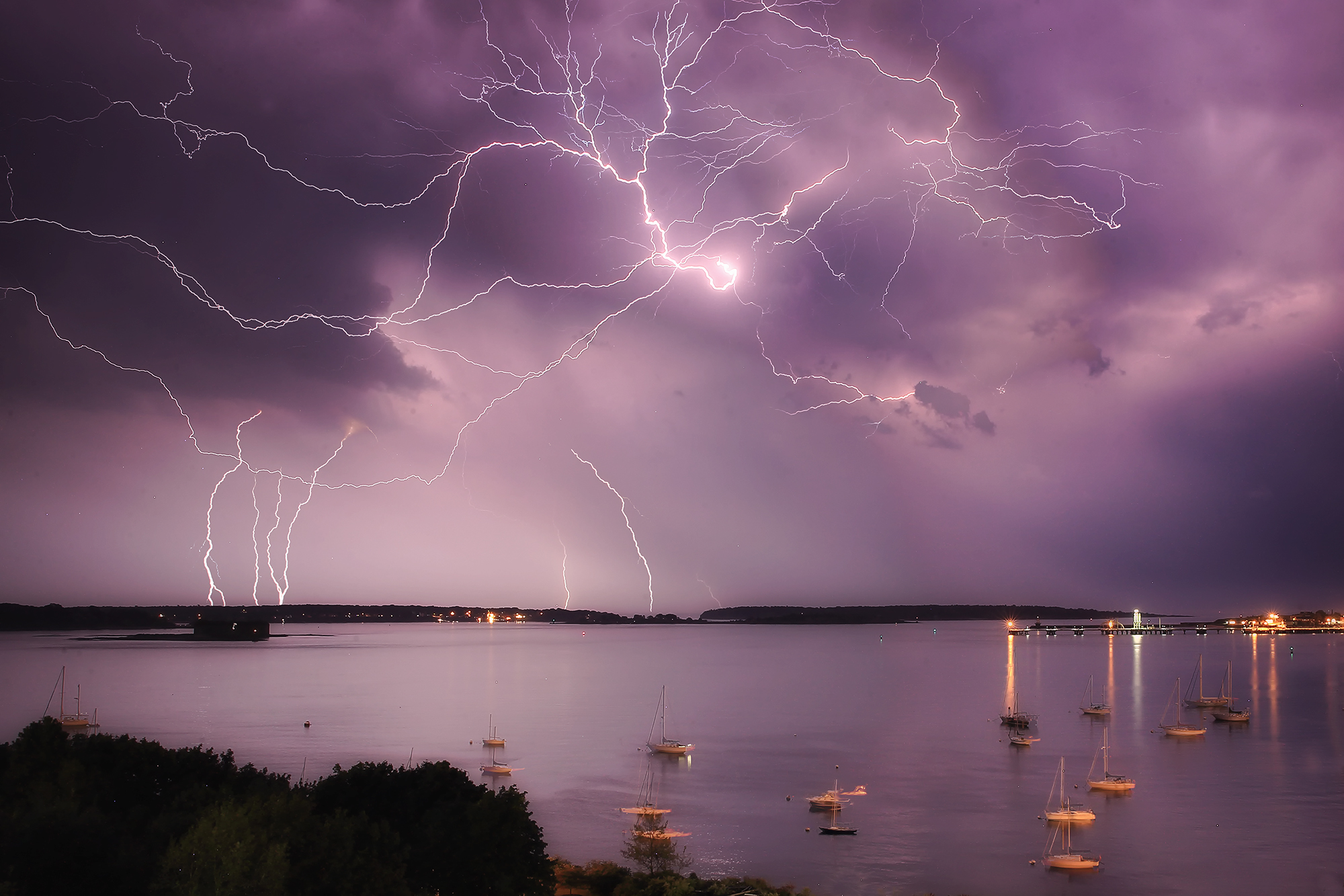 Forked lightning splits the night sky over a rugged horizon—electromagnetism alive in the wild